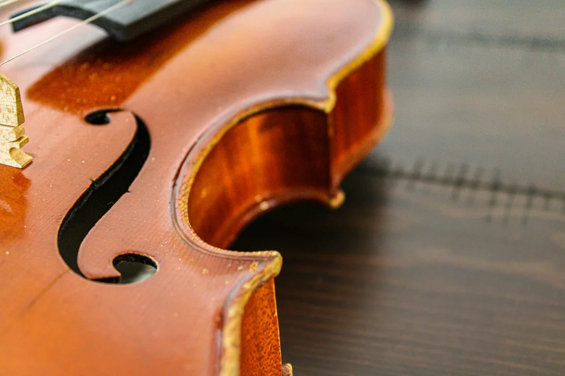 Violín apoyado sobre una mesa de taller, con la tapa de abeto y los oídos visibles a contraluz